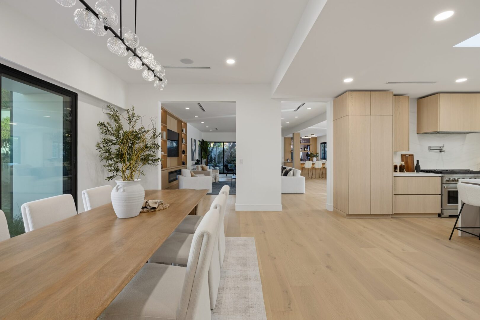 Wood dining table and upholstered chairs face the kitchen, with the living area visible beyond.