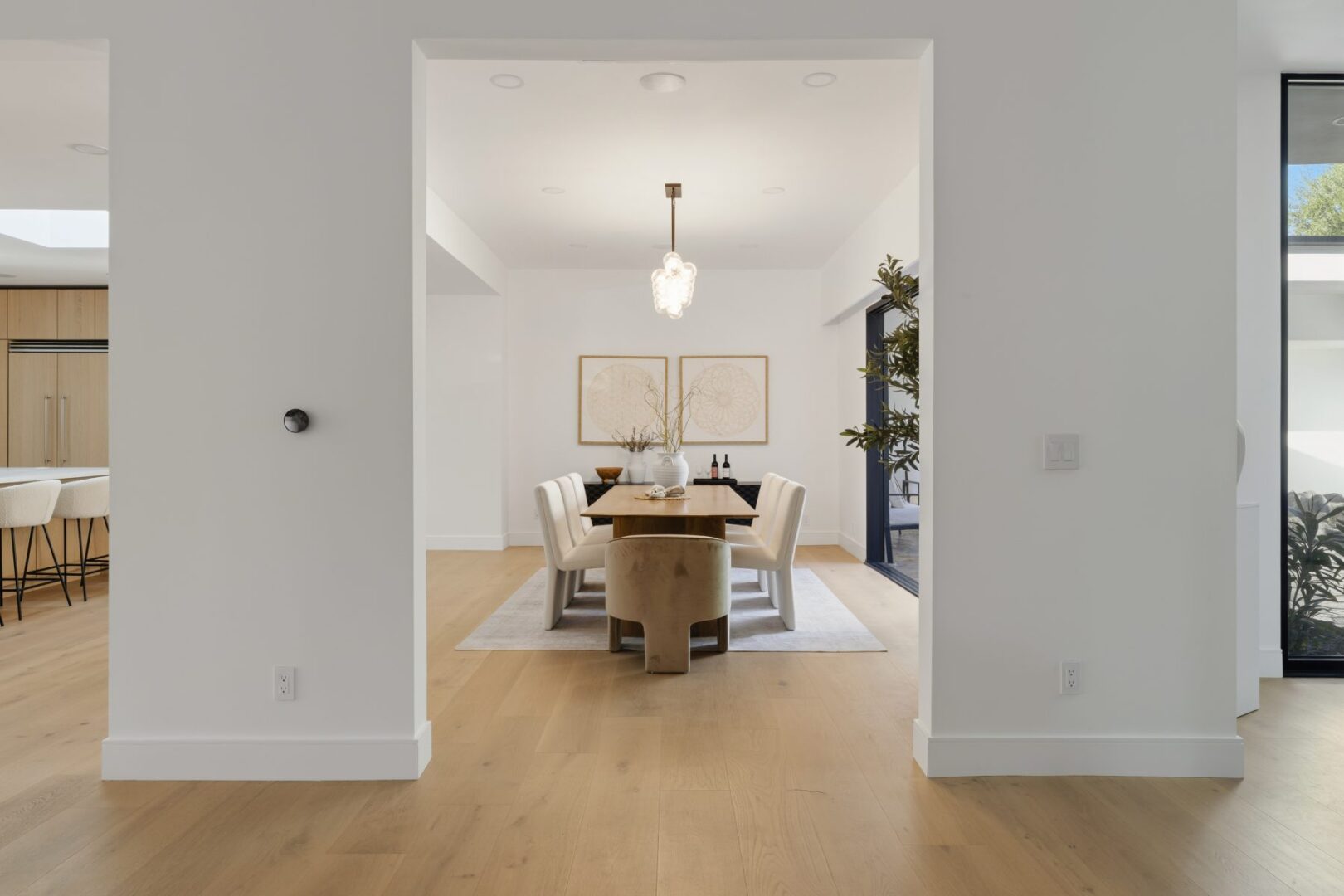 Dining room with a wood table, upholstered chairs, pendant fixture, and wide opening to the main space.