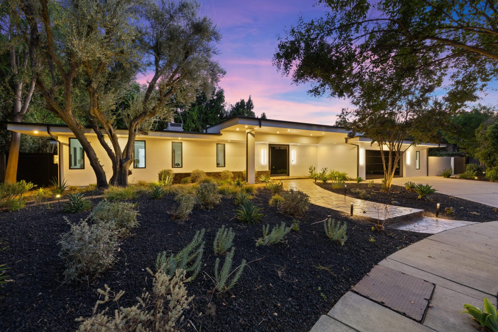 Single-story home with a broad entry walkway, low rooflines, and drought-tolerant landscaping.