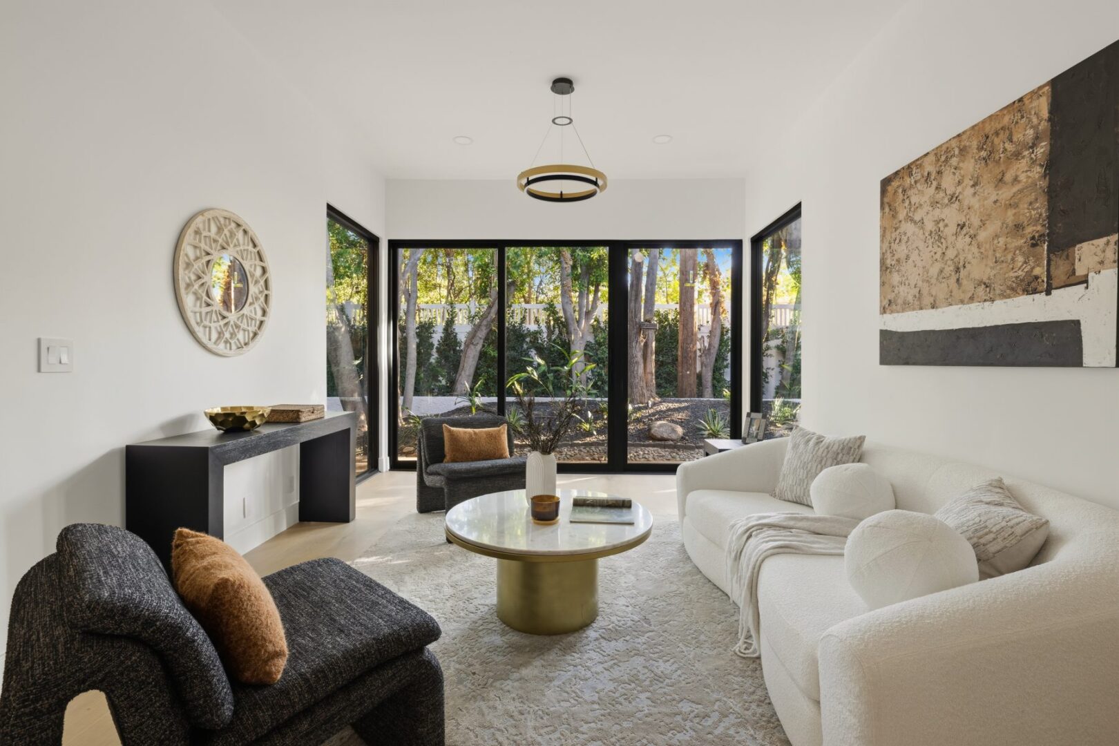 Living room with white and dark sofas, a round coffee table, and wide garden-facing windows.