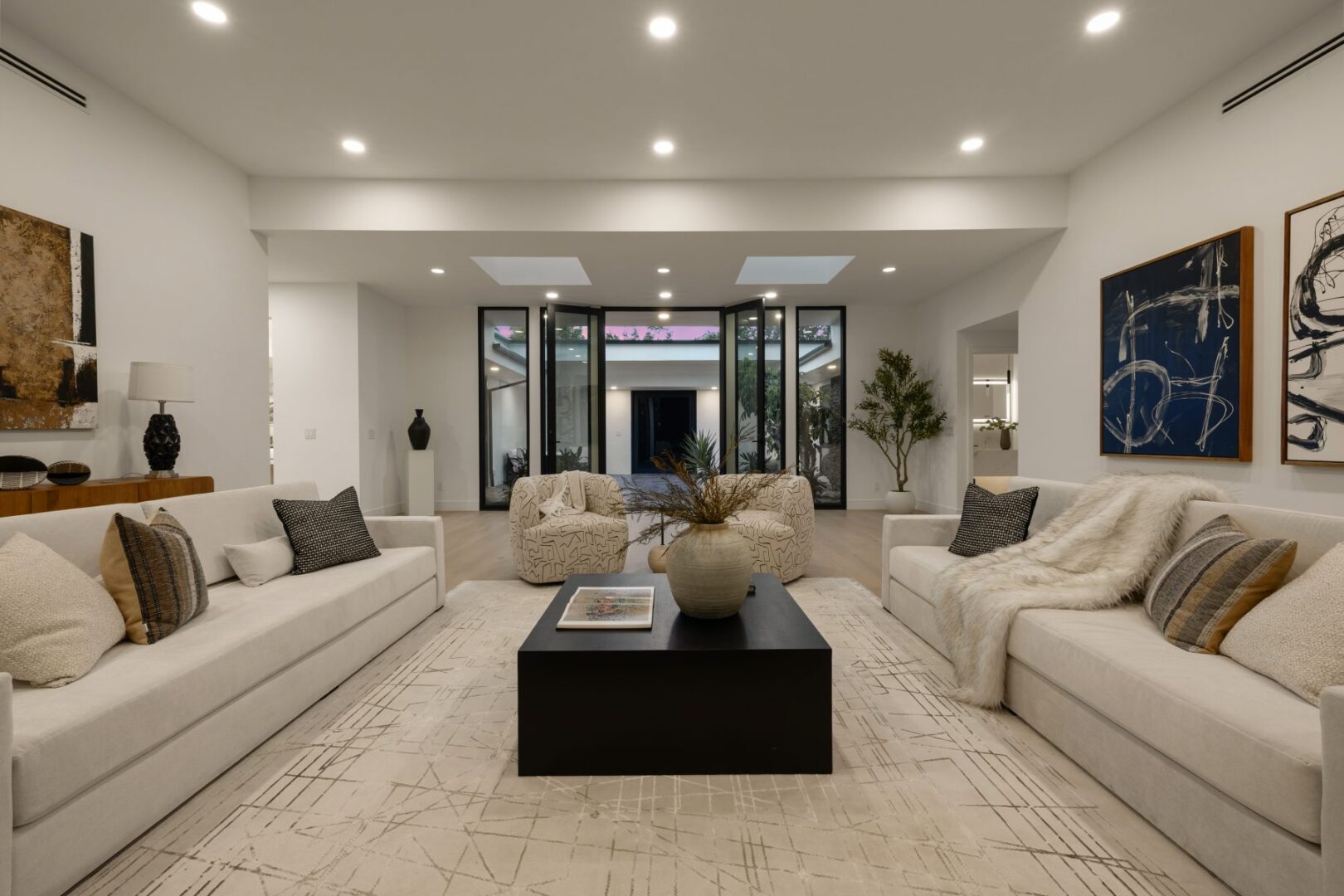 Living room with facing sofas, a central coffee table, and glass doors opening toward the courtyard.