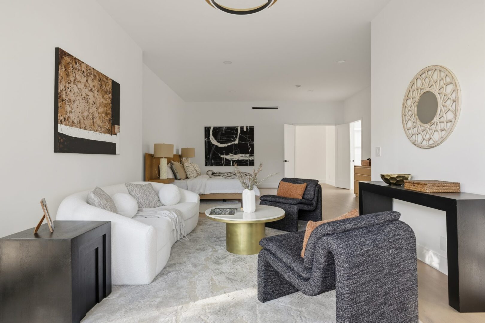 Living room seating faces a bed, with a coffee table and console along the walls.