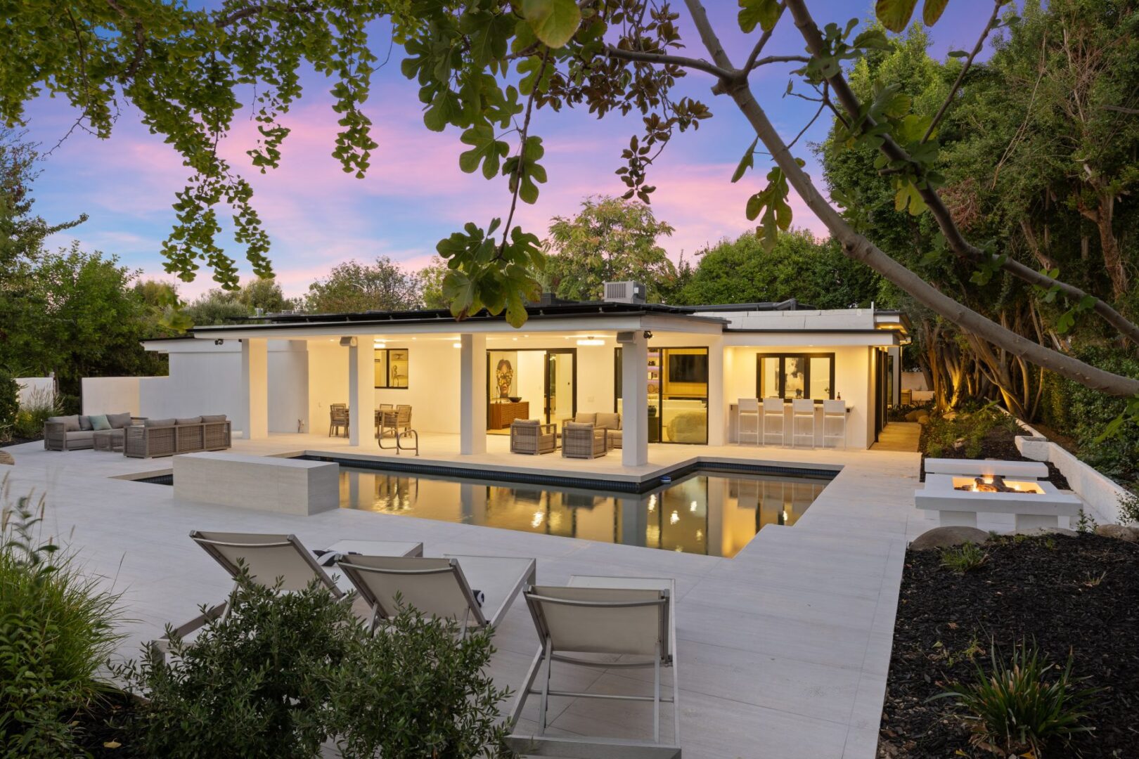 Swimming pool and tiled deck connect to the home’s covered patio and outdoor dining area.
