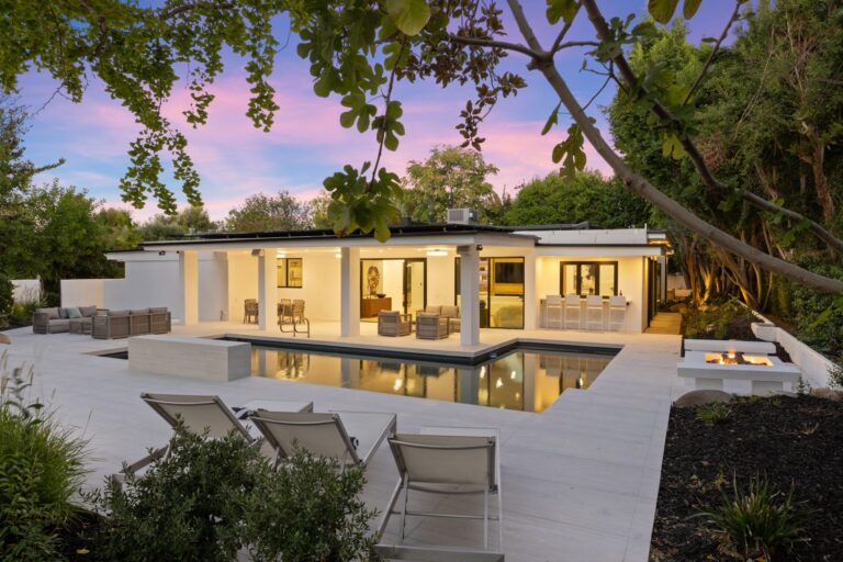 Swimming pool and tiled deck connect to the home’s covered patio and outdoor dining area.