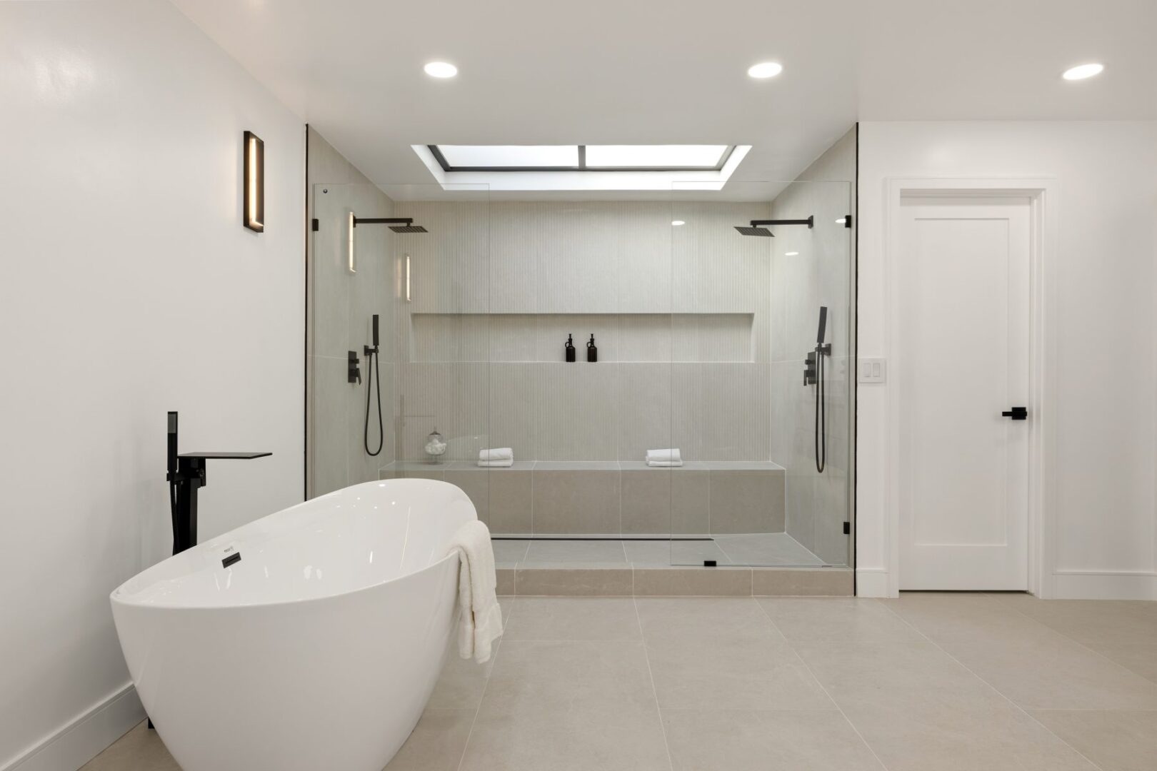 Bathroom with a freestanding tub, glass-enclosed shower, built-in bench, and recessed niche.