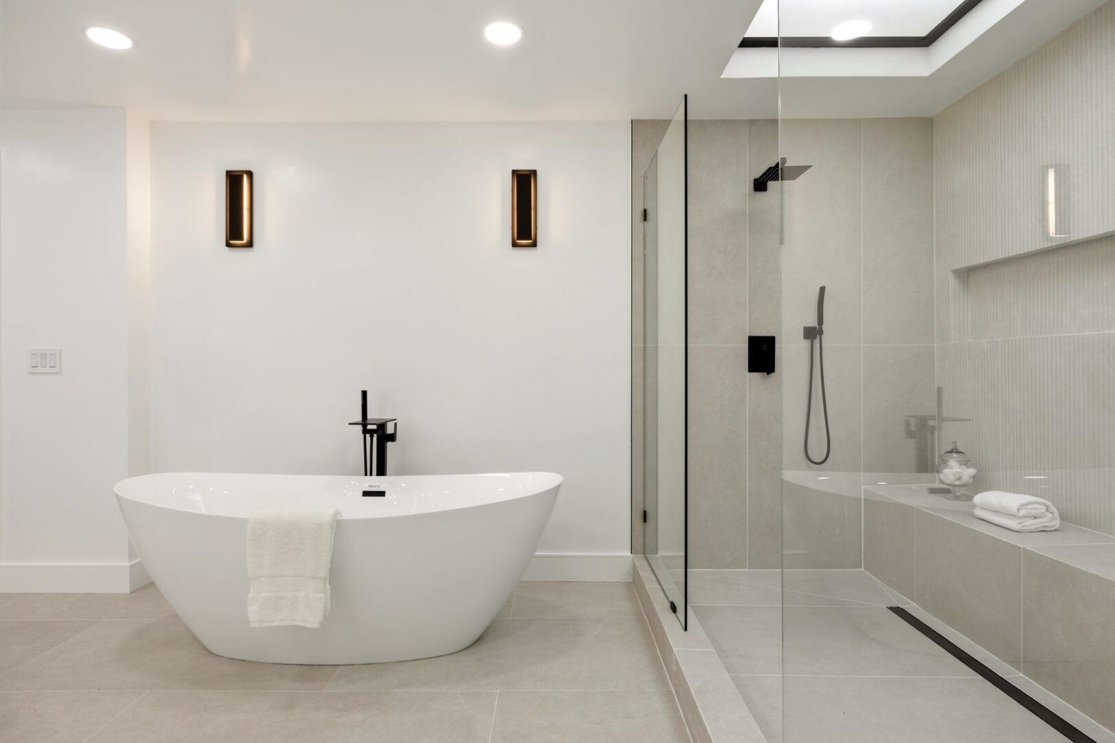 Bathroom with a freestanding tub beside a glass shower and built-in tiled bench.