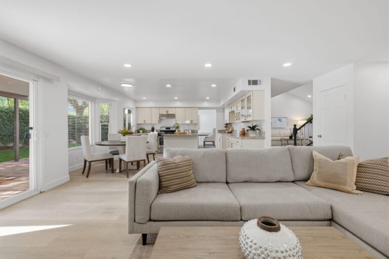 Open living space with large sectional couch and views to the kitchen and outdoor area