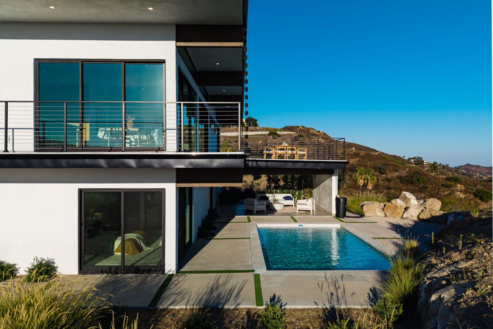 View of the pool and patio area with modern home in the background.