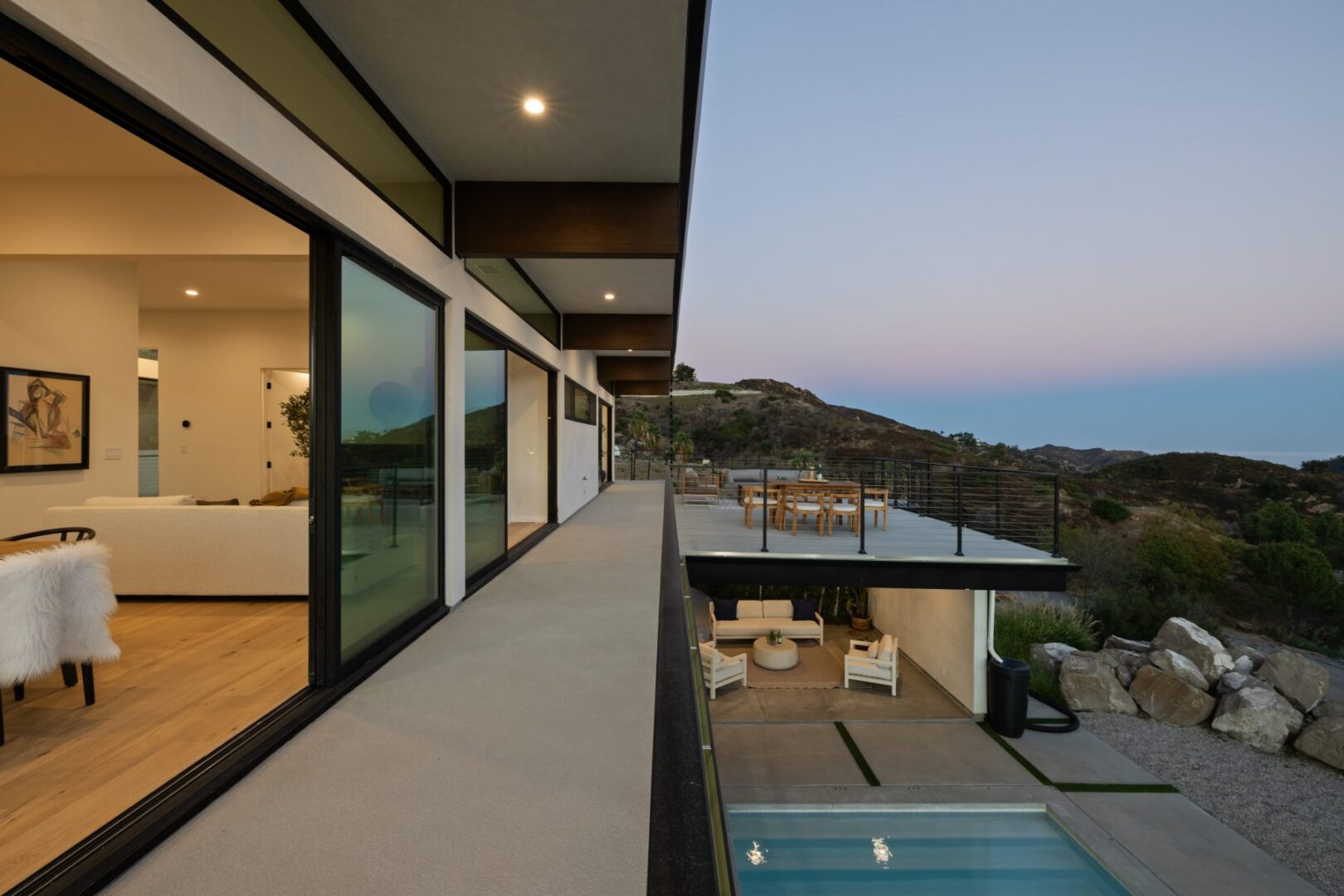 Balcony view overlooking the landscape at dusk, with seating and dining area visible.