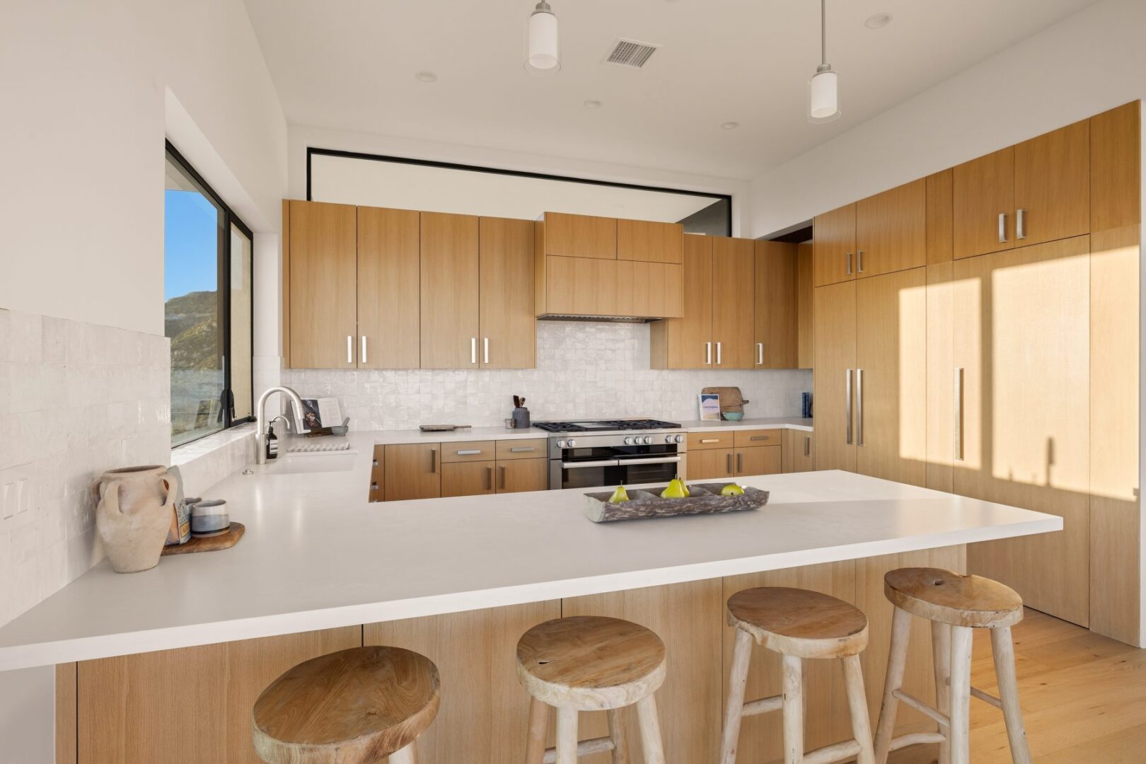 Modern kitchen with wooden cabinets and white countertops, natural light streaming in.