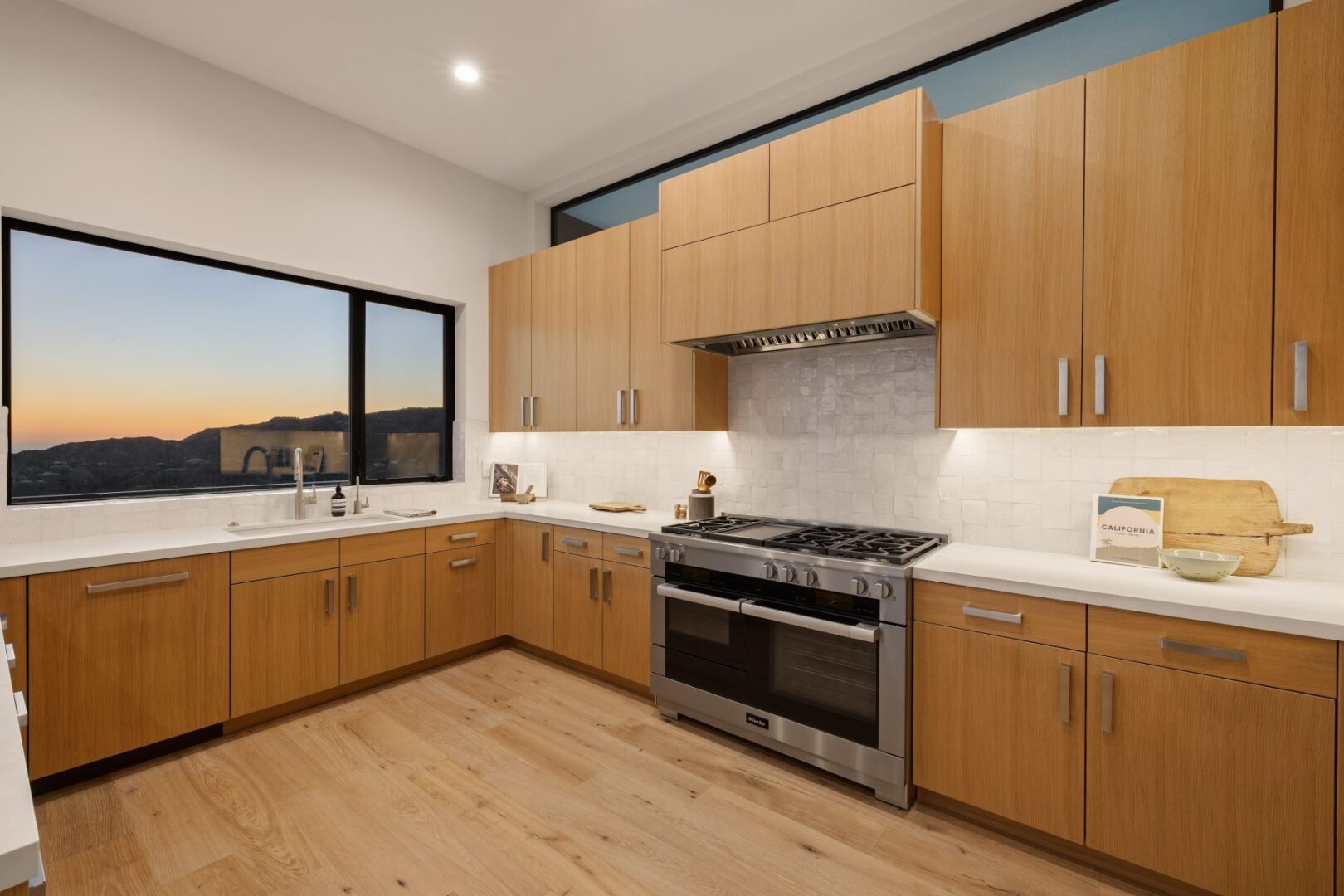 Contemporary kitchen with wooden cabinets and a view of the mountains at sunset.