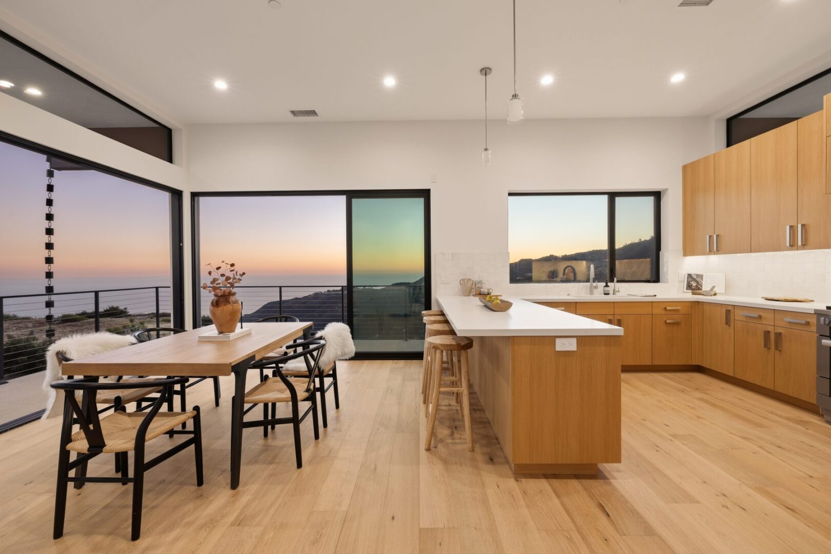 Modern kitchen with an island, dining table, and ocean views through large windows.