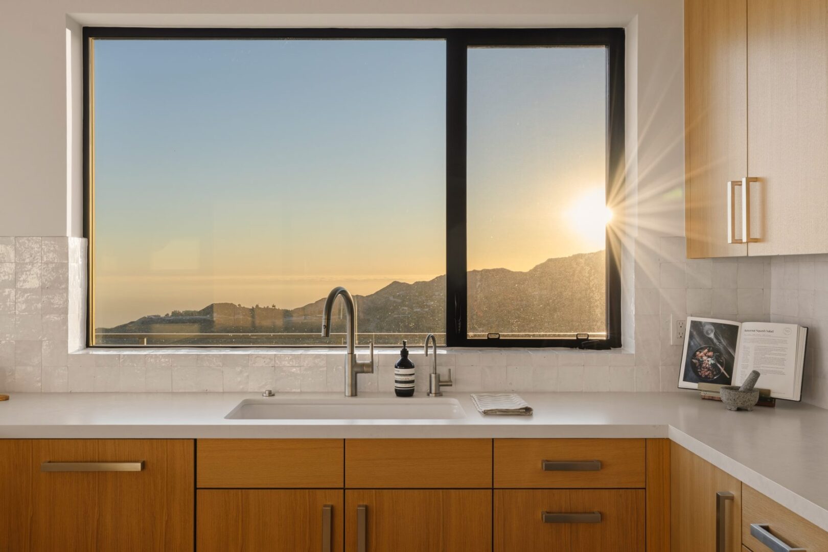 Close-up of the kitchen sink with a view of the sunset through the window.