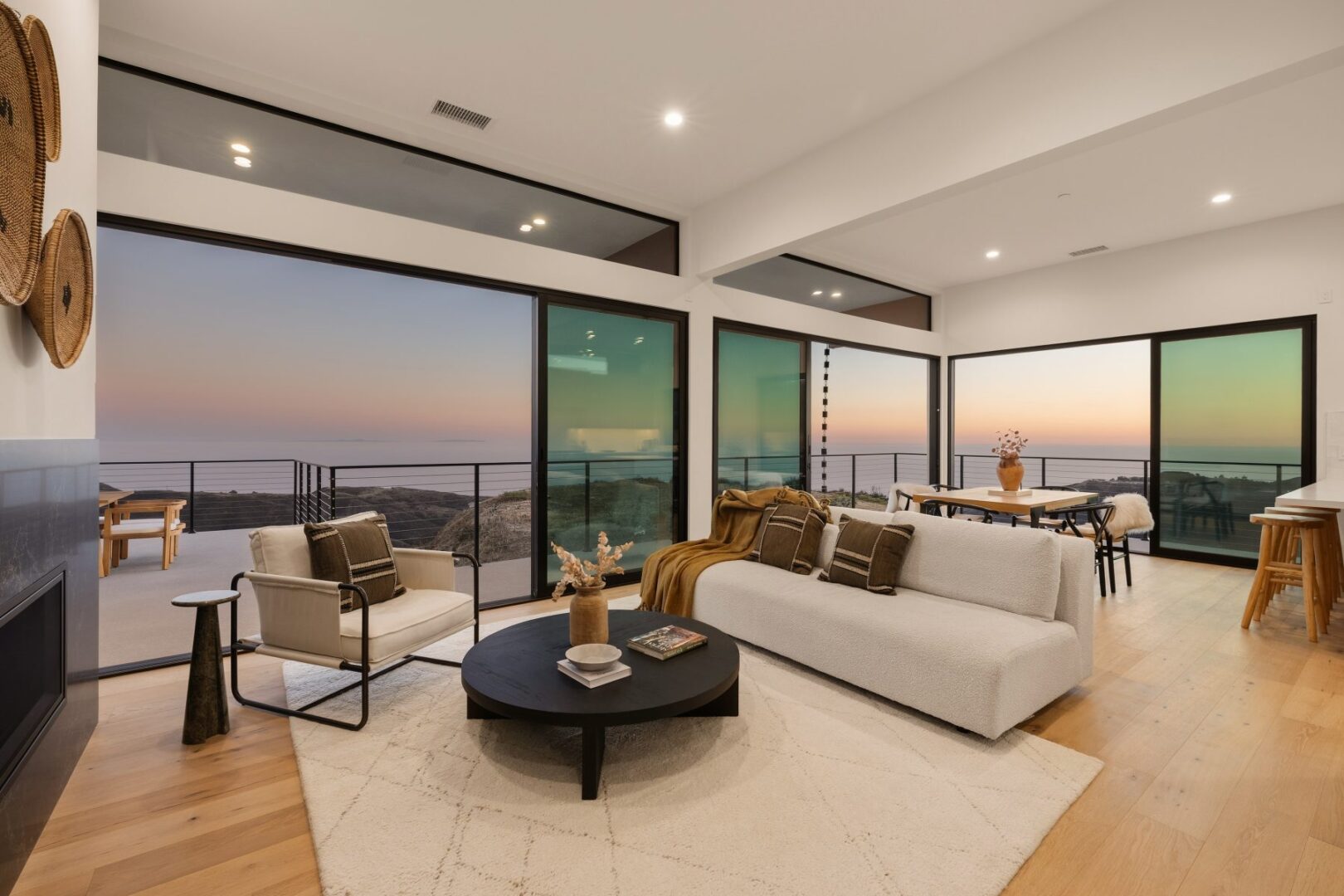 Spacious living room with large windows showcasing a sunset view over the ocean.