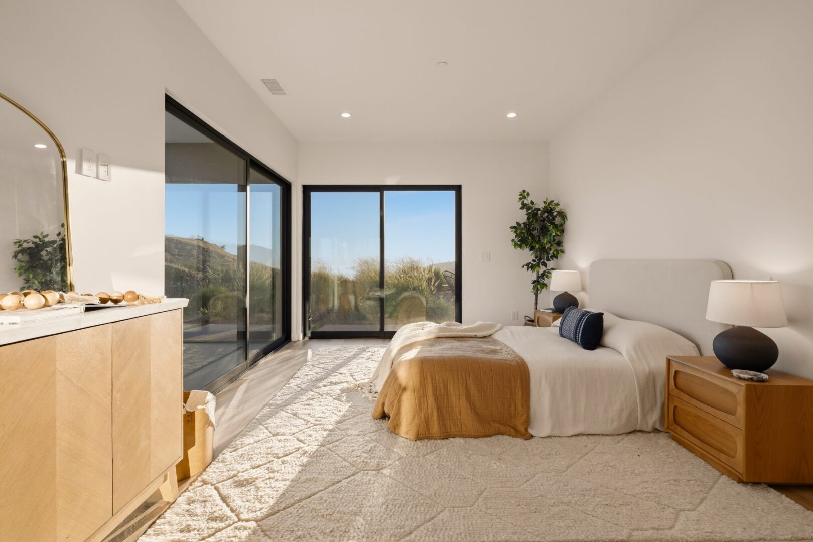 Bright primary bedroom with large windows and a cozy bed.