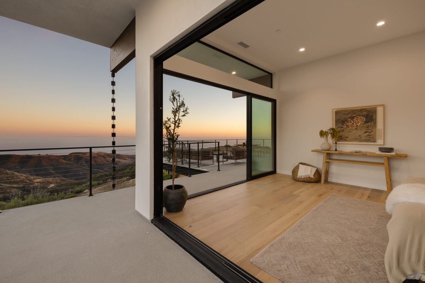 Open primary bedroom with sliding doors leading to a balcony and sunset view.