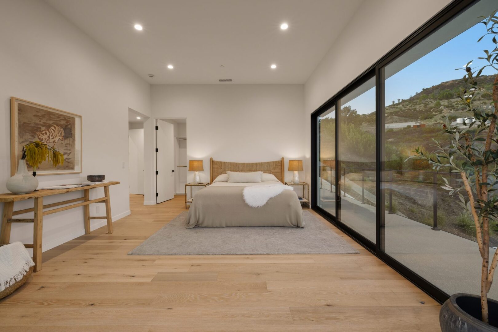 Bright primary bedroom with large windows and a view of the surrounding landscape.
