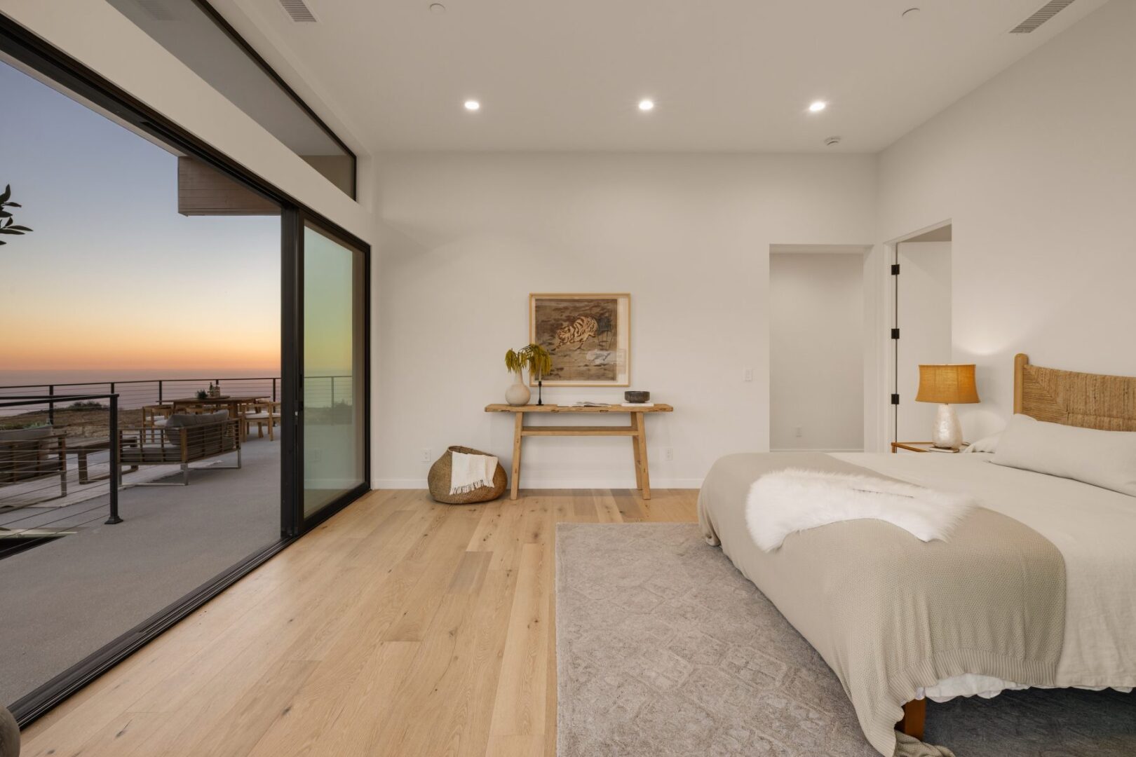 Cozy primary bedroom with a view of the outdoor patio and sunset.