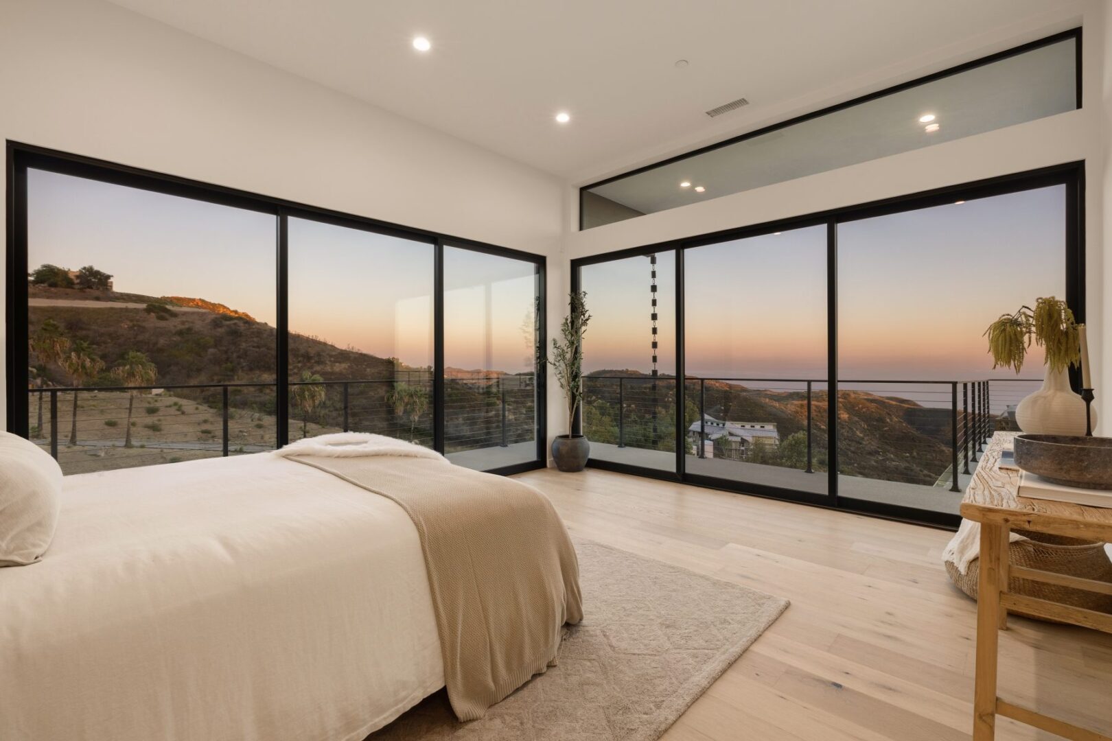 Spacious primary bedroom with expansive windows showcasing a sunset view.