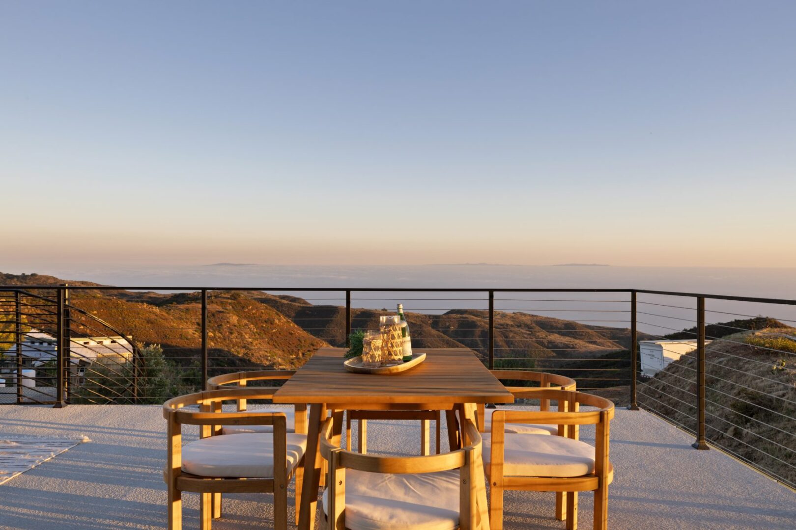 Dining table on a balcony with mountain views at sunset.
