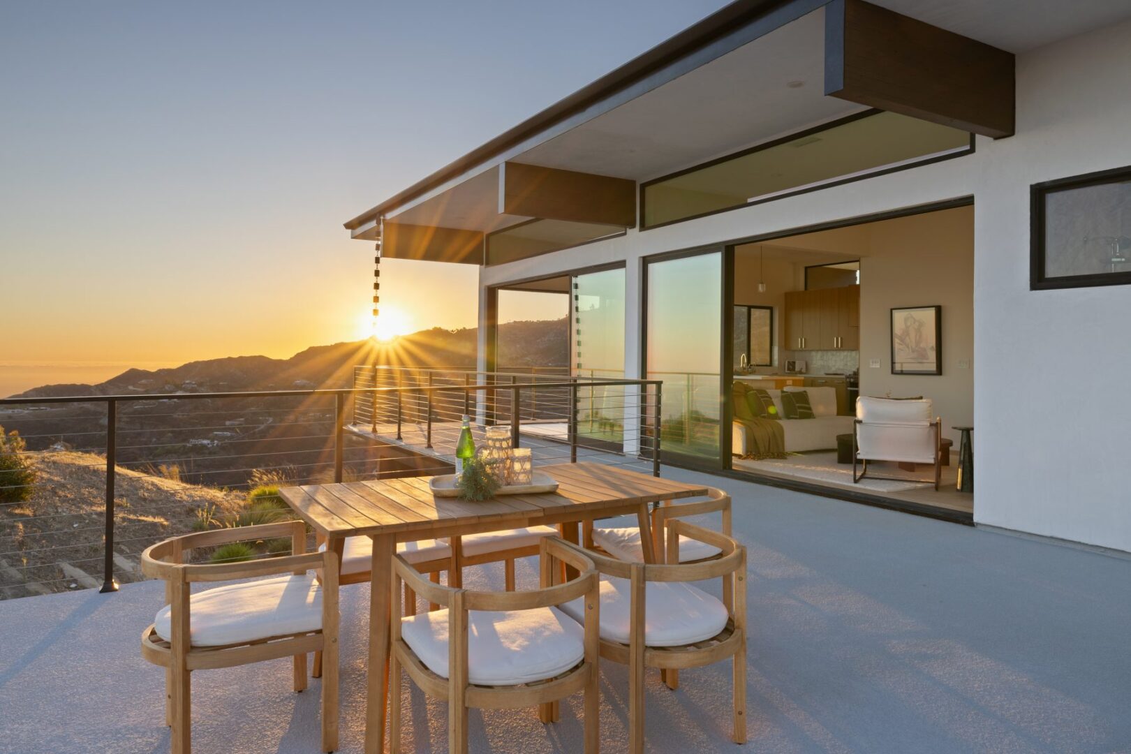 Dining area on a balcony with sunset and mountain views.