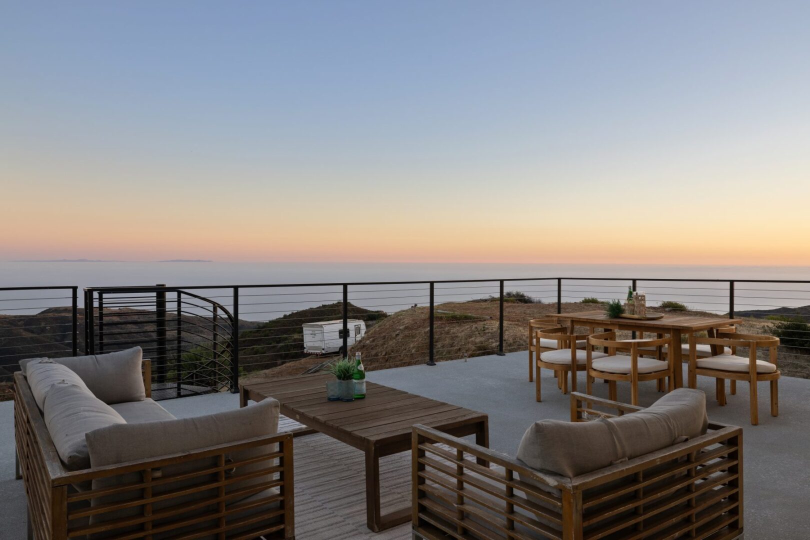 Outdoor seating area with a view of the sunset over the landscape.