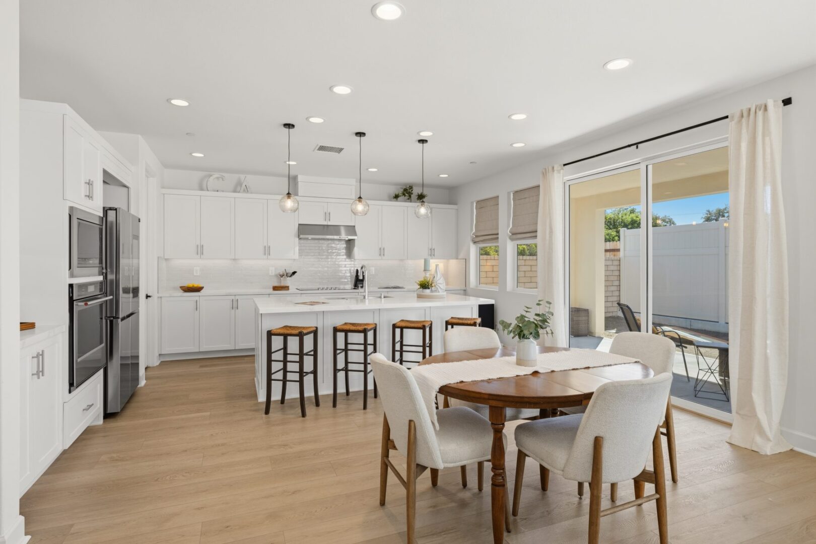 Dining table and chairs face the kitchen island, with sliding doors opening to a fenced patio.