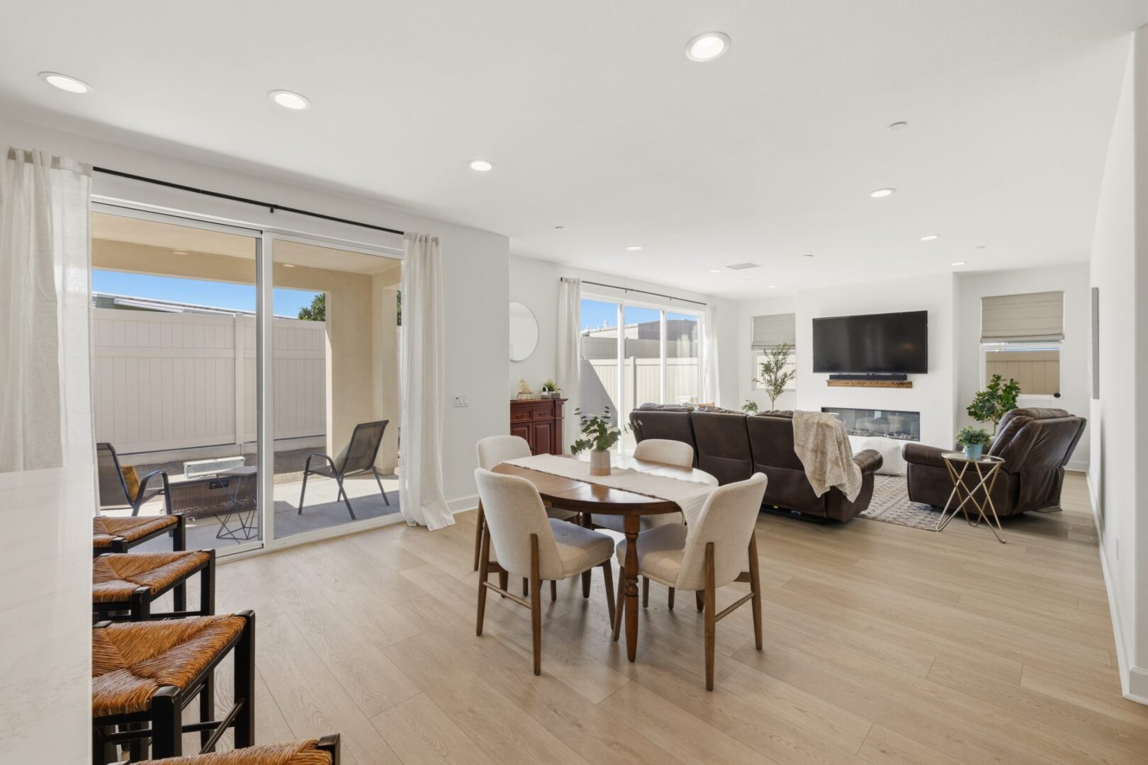 Dining table sits between the living room and sliding doors that open to a fenced patio.