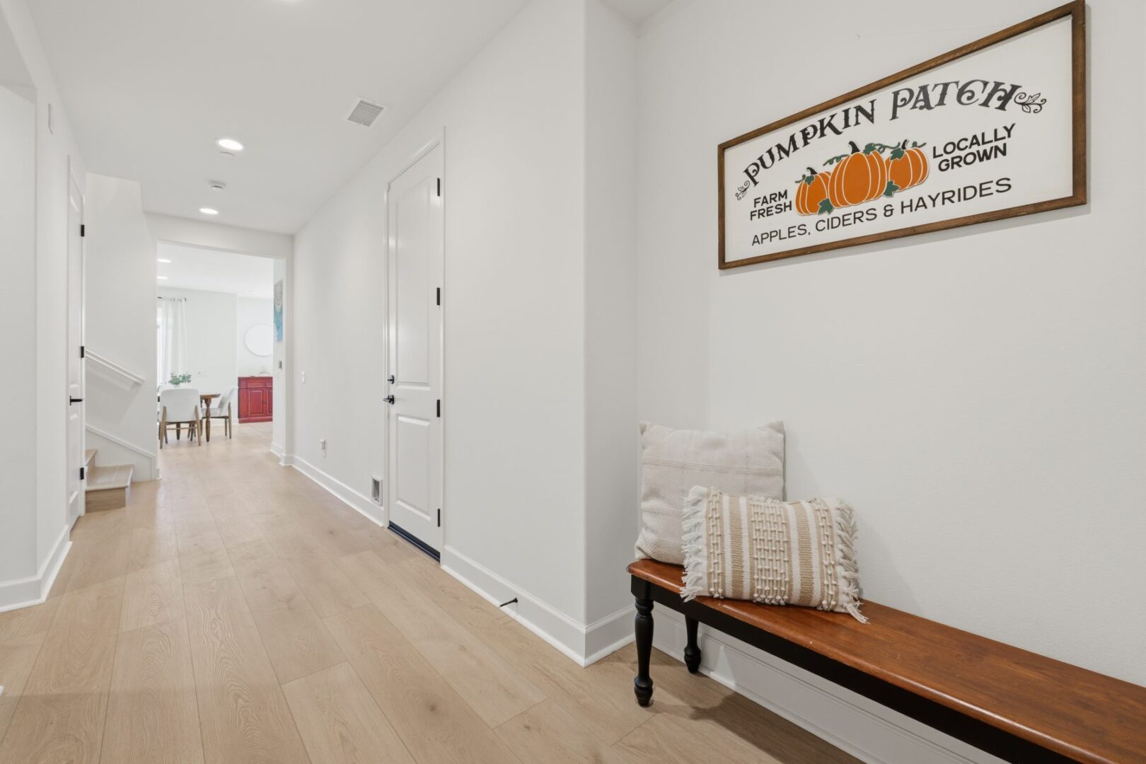 Hallway with a wood bench, decorative sign, and an open passage to the dining area.
