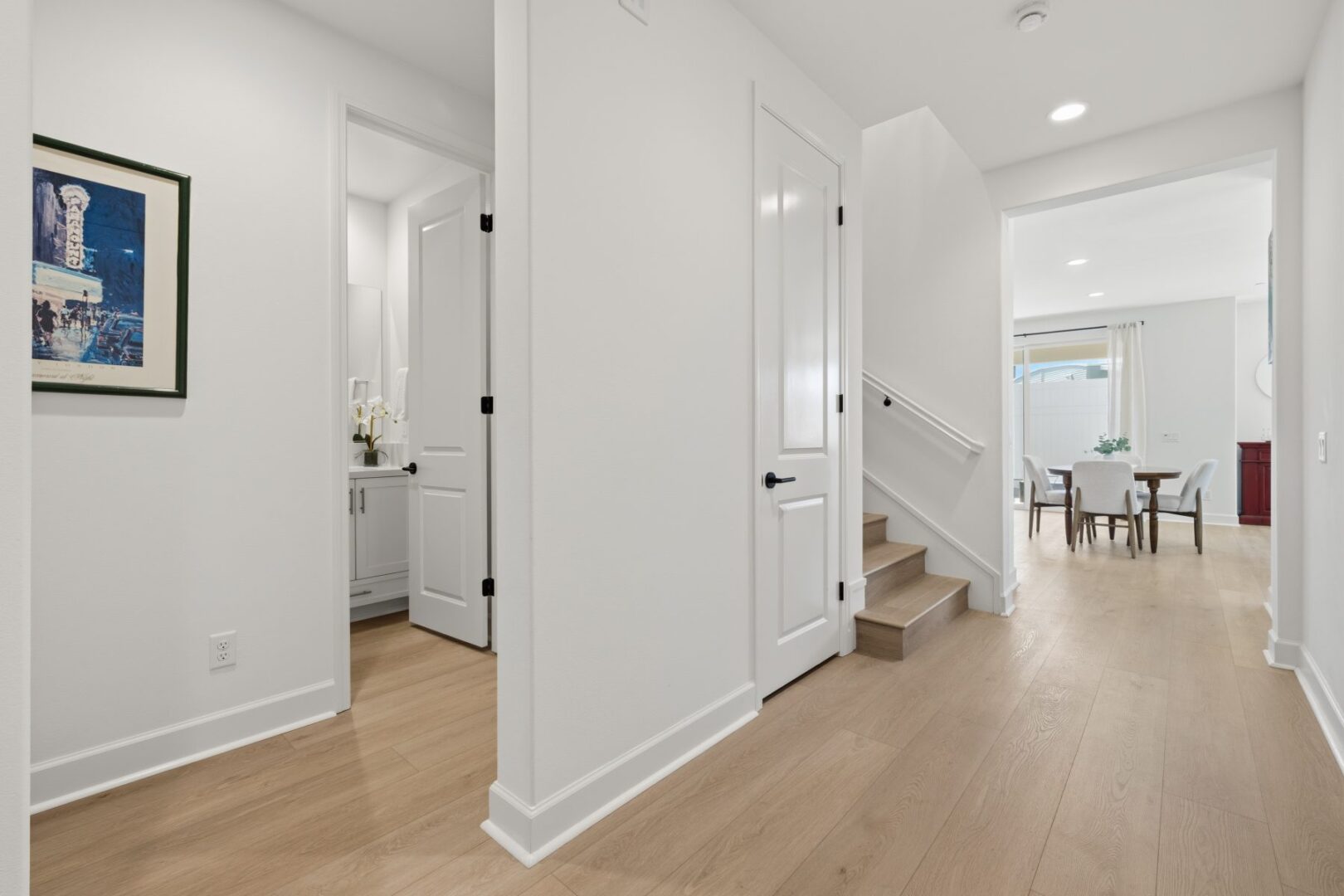 Central hallway with stairs, several doorways, and an open view toward the dining room.