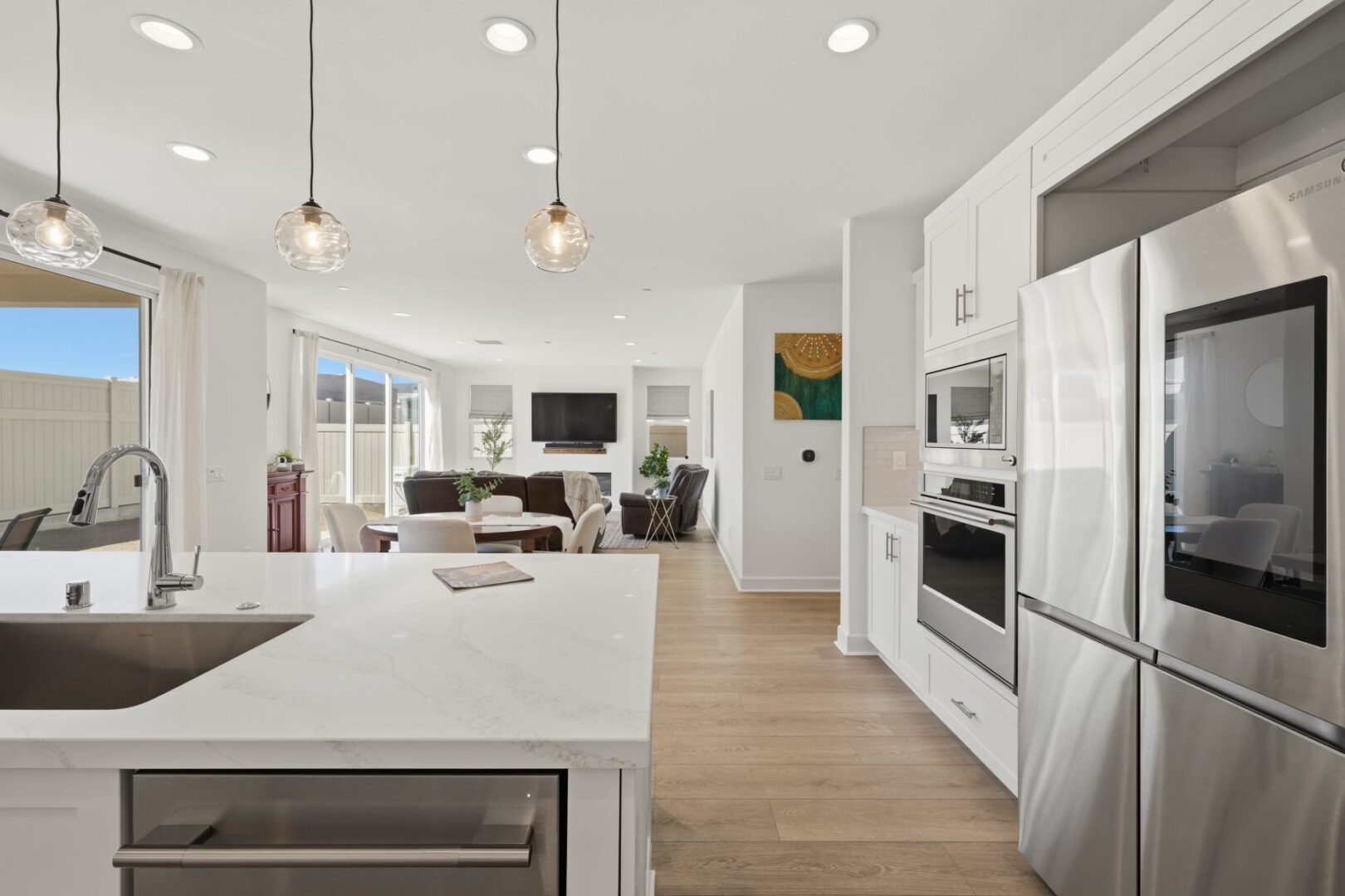 Kitchen island sink faces the dining and living areas, with stainless appliances along the cabinetry.