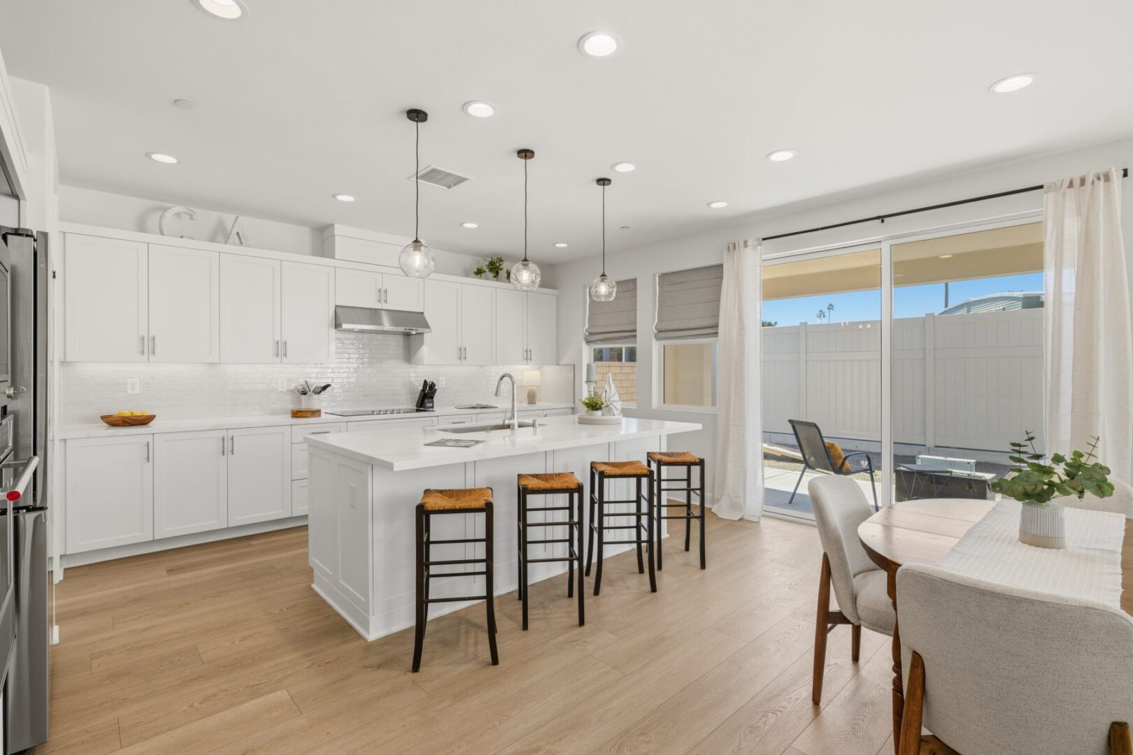 Kitchen with a large island, four bar stools, white cabinets, and sliding doors to the patio.