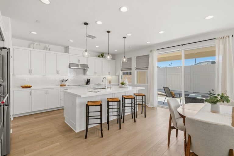 Kitchen with a large island, four bar stools, white cabinets, and sliding doors to the patio.