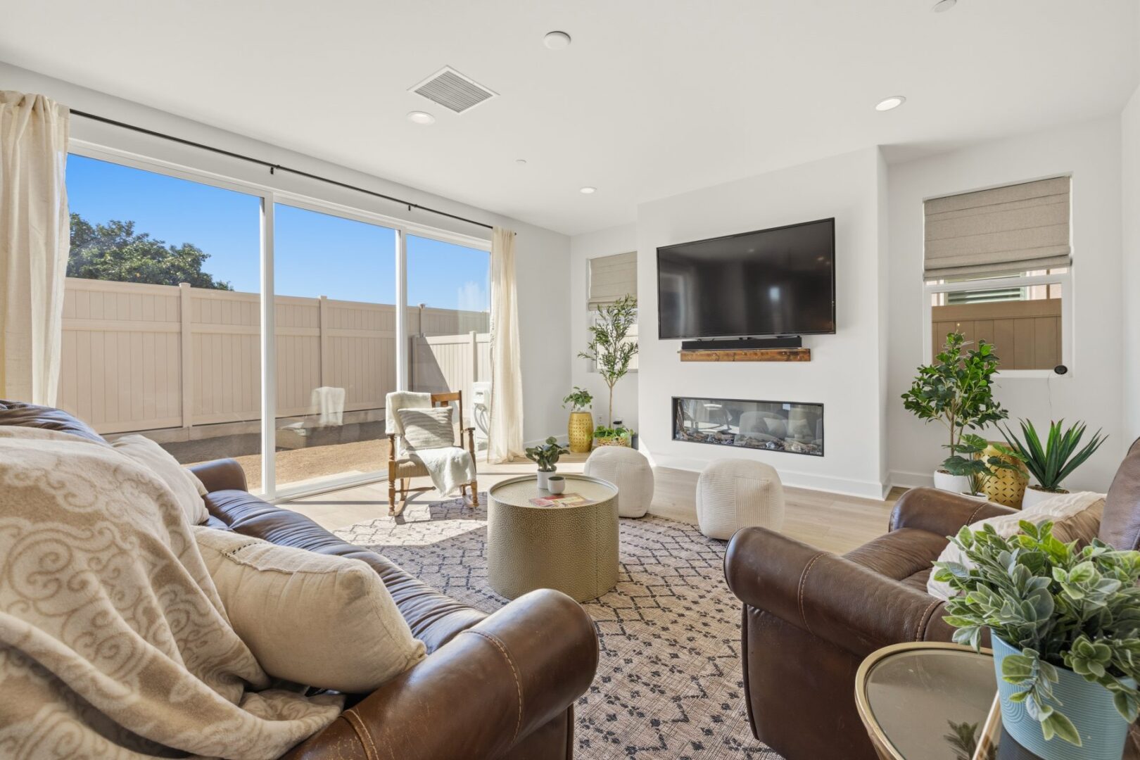 Living room with sofas, a television, and fireplace beside wide sliding doors to the fenced yard.