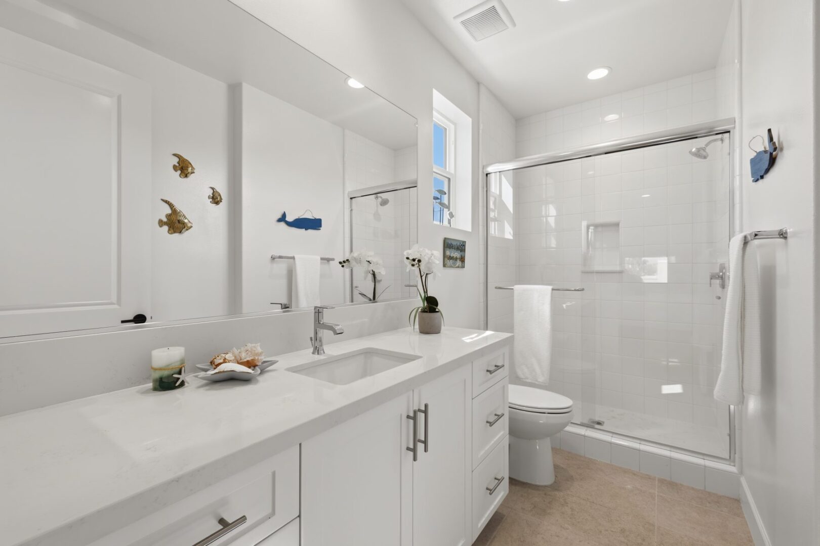 Bathroom with a long vanity, undermount sink, large mirror, and glass-enclosed tiled shower.