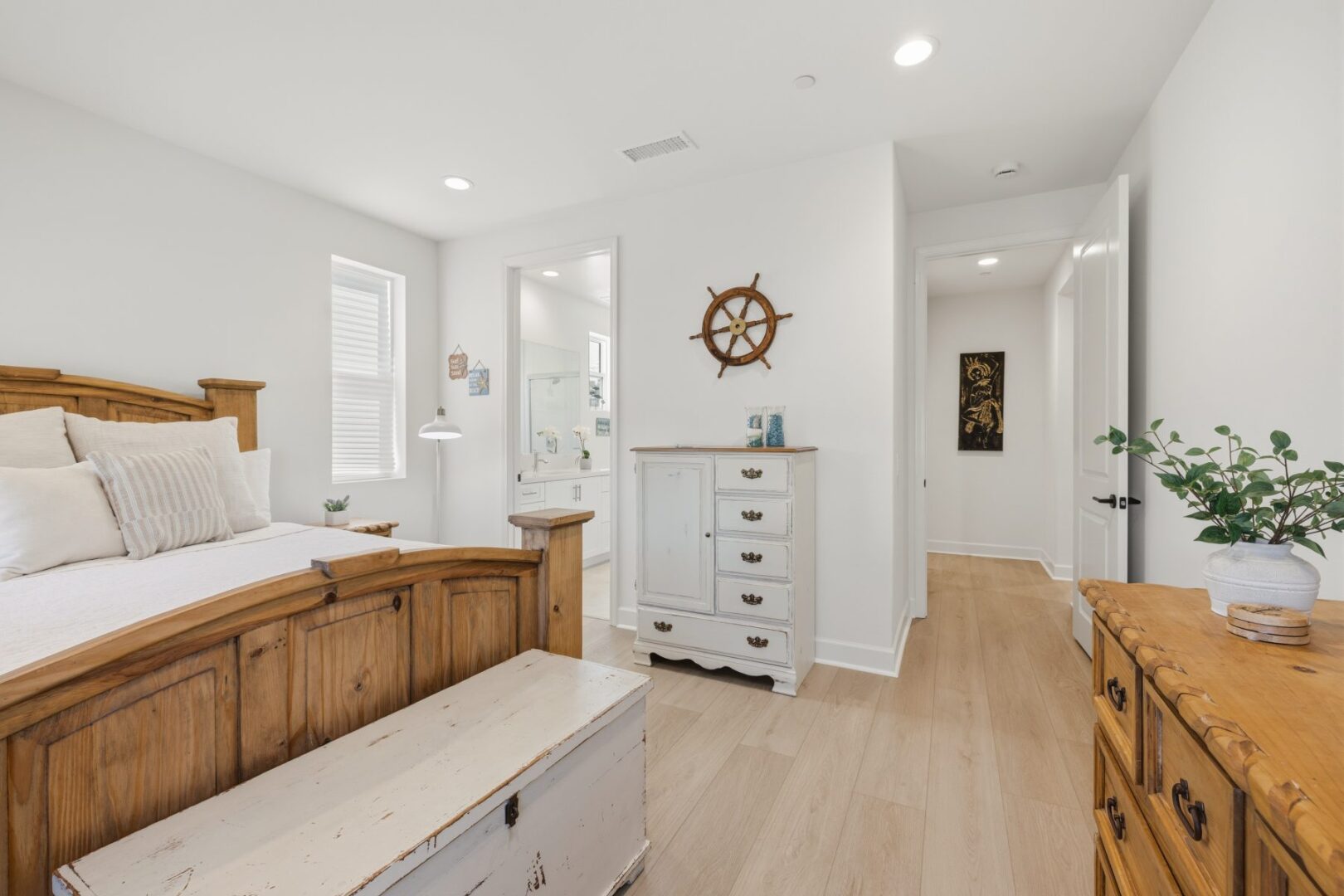 Bedroom with a wood bed and dresser, opening to an ensuite bathroom and adjoining hallway.